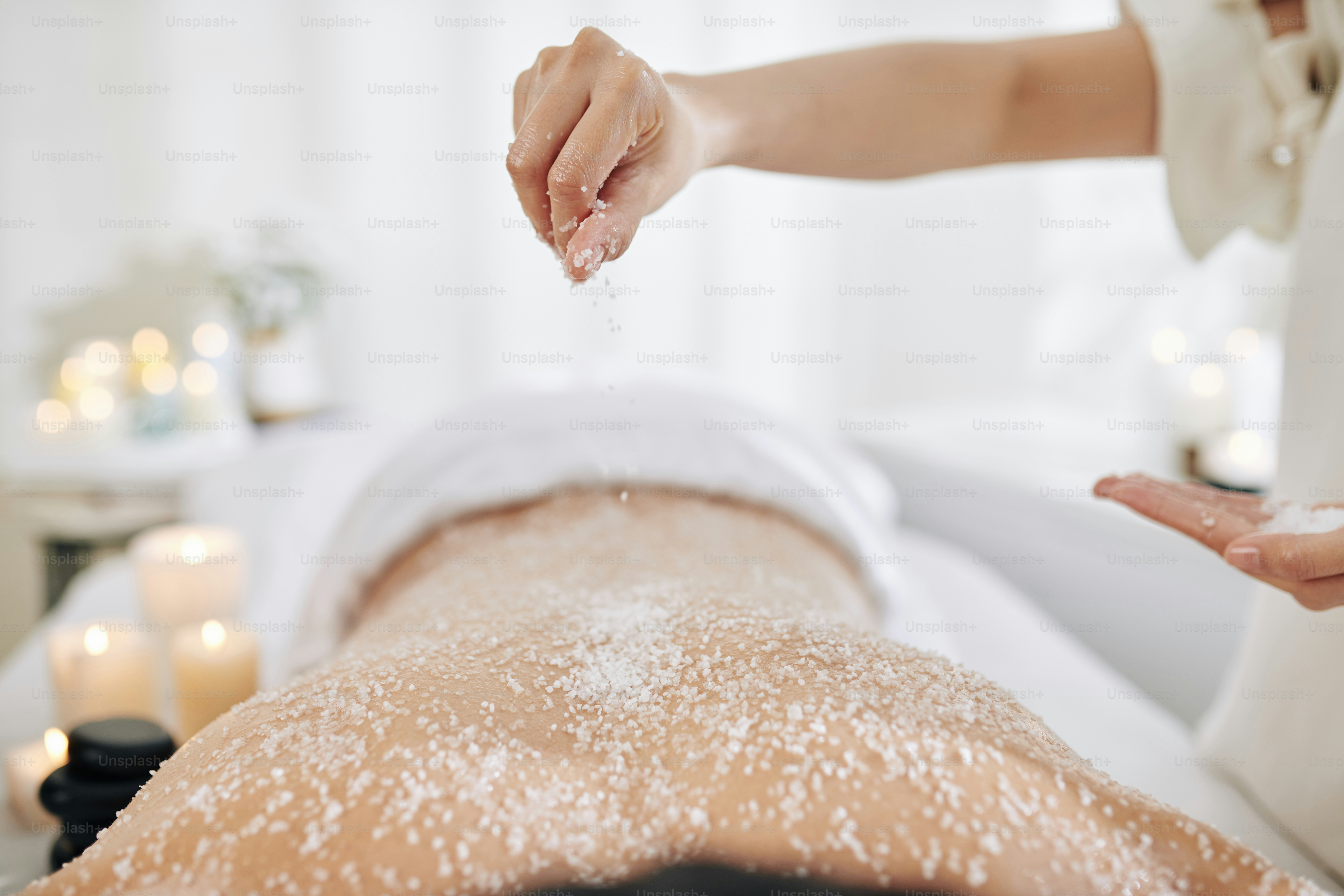 Beautician applying sea salt scrub on back of male client photo – Spa ...