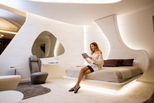 Hübsche junge Frau mit Tablet sitzt in der luxuriösen Wohnung