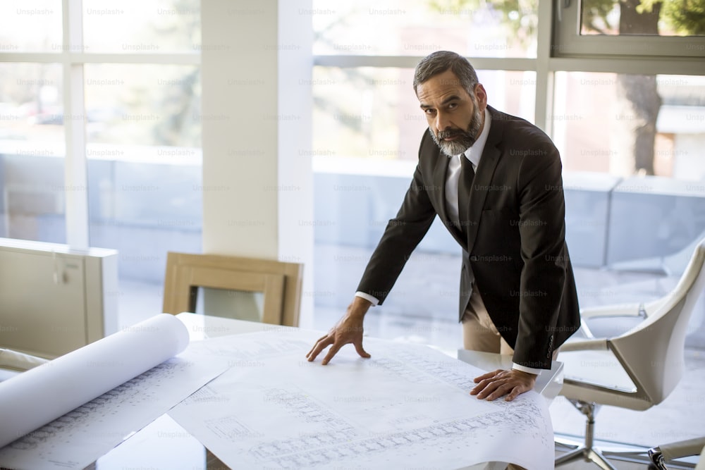 Handsome architect checking plans and blueprints in the office