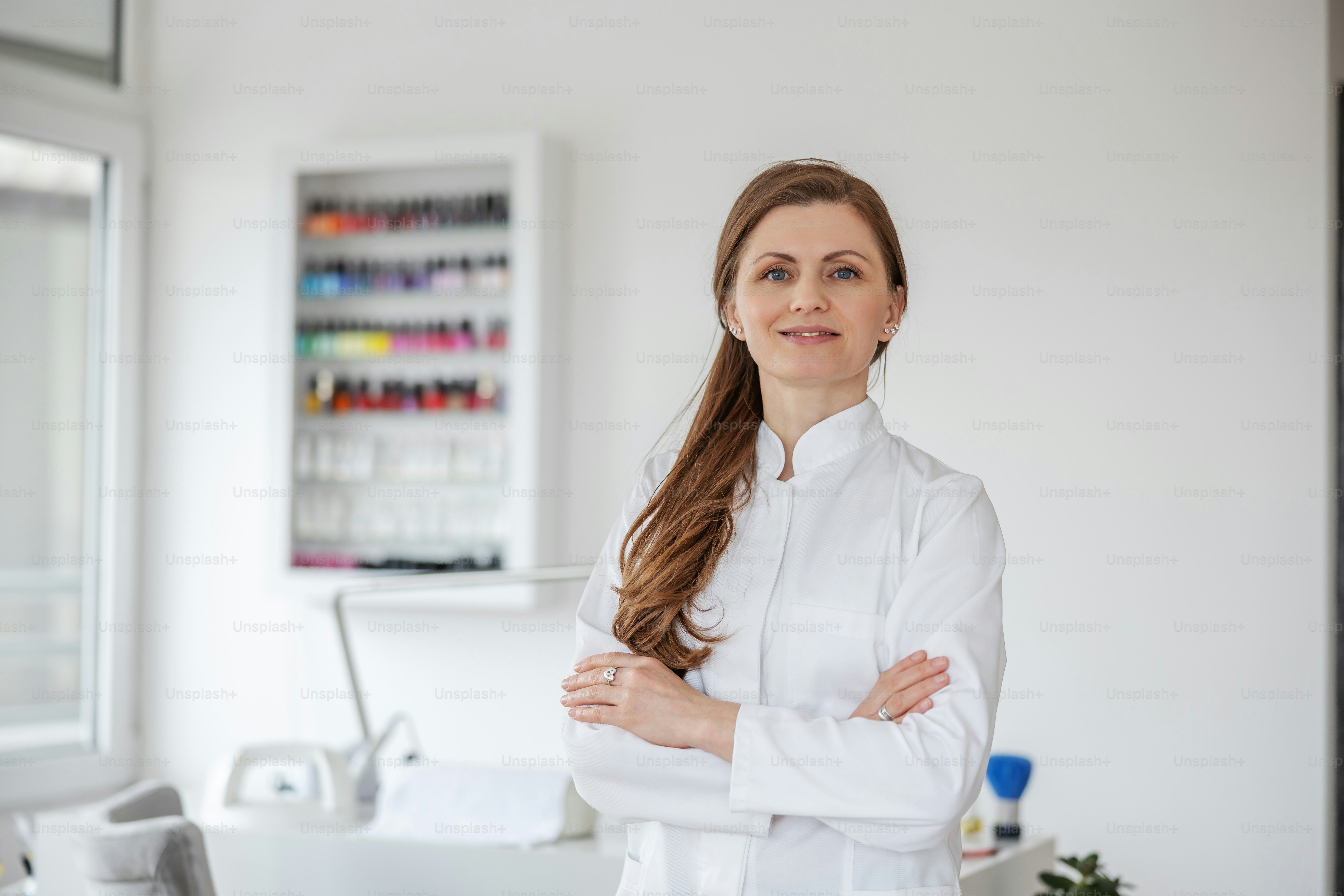 Retrato de esteticista de pie en el salón de belleza con los brazos cruzados.