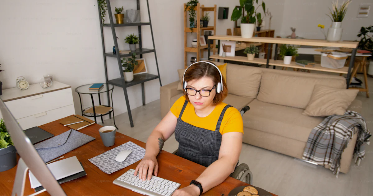 Concentrated young female programmer sitting in wheelchair and using ...