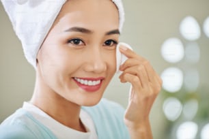 Lächelnde attraktive junge vietnamesische Frau, die ihr Make-up abwischt