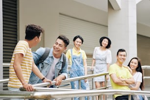 Cheerful young Asian university students standing in front of entrance of building