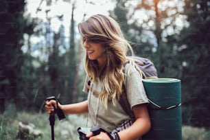 Hiker woman with backpack walking in forest in summer. Selective focus.