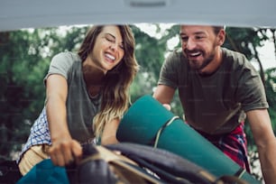 Young couple having fun while unpacking camping equipment