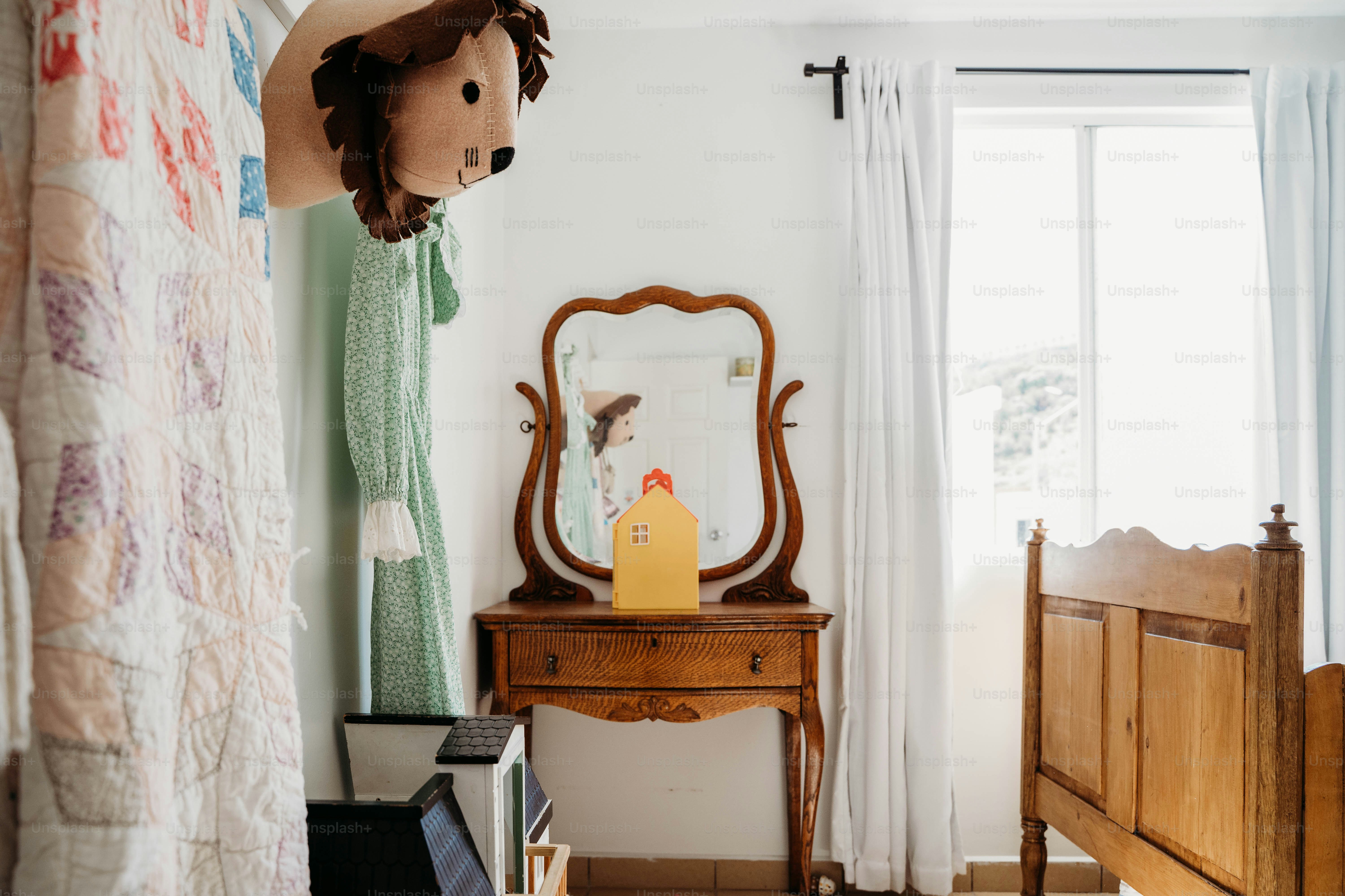 a bedroom with a bed, dresser, mirror and a teddy bear
