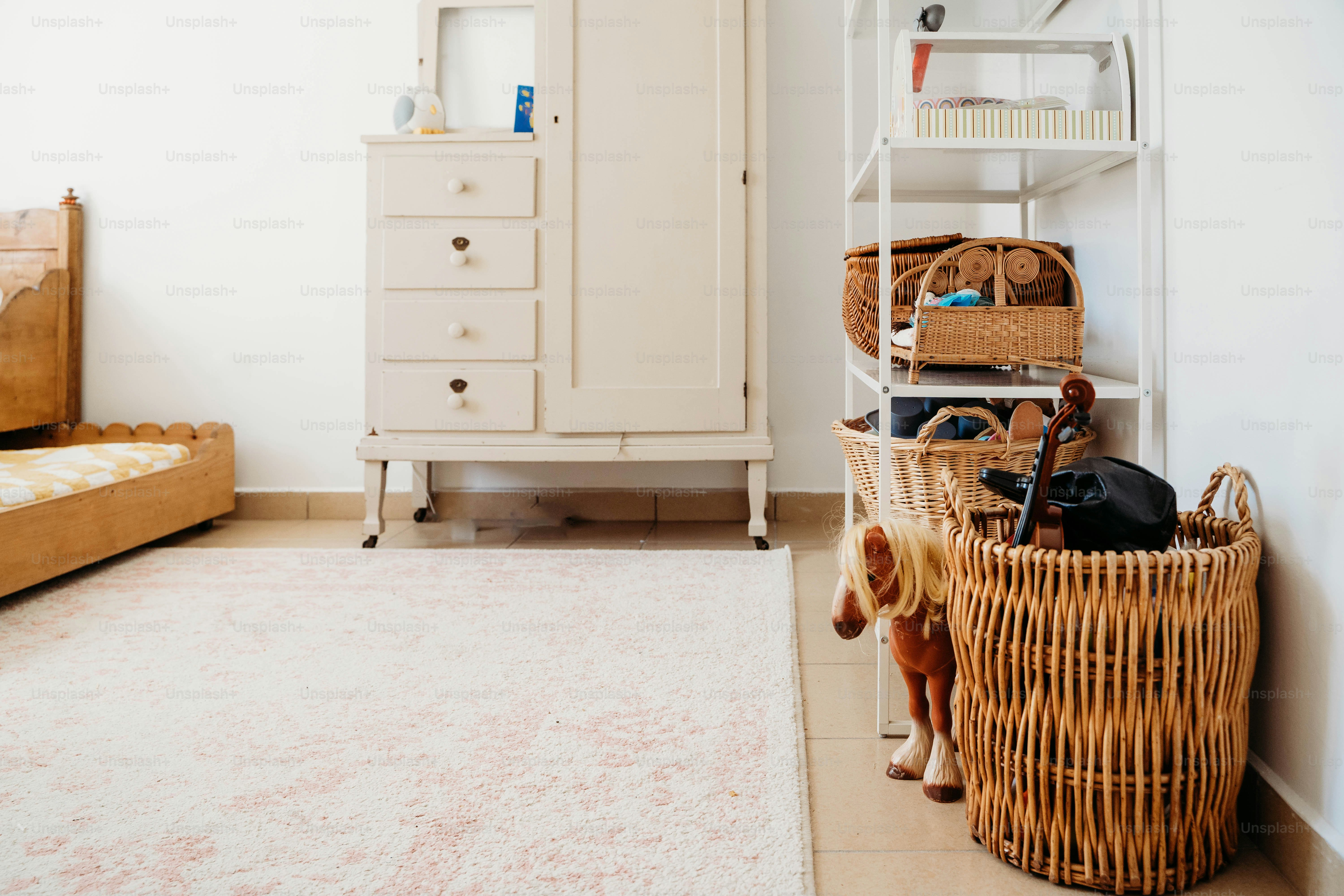 a room with a bed, a dresser, and a basket on the floor