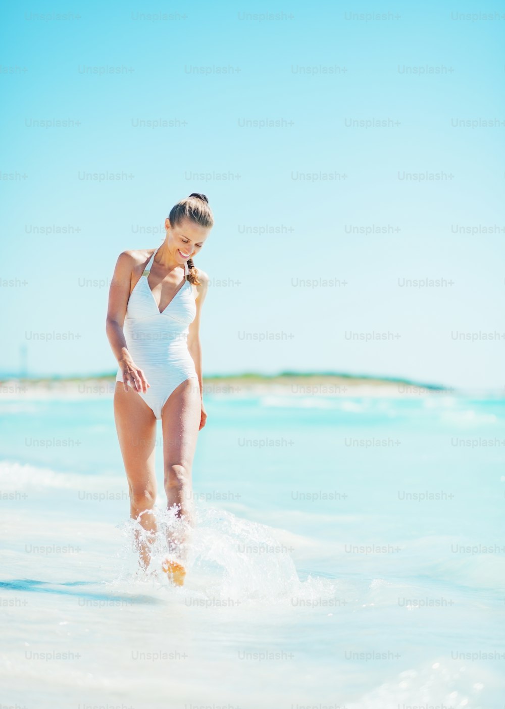 Full length portrait of smiling young woman walking at seaside
