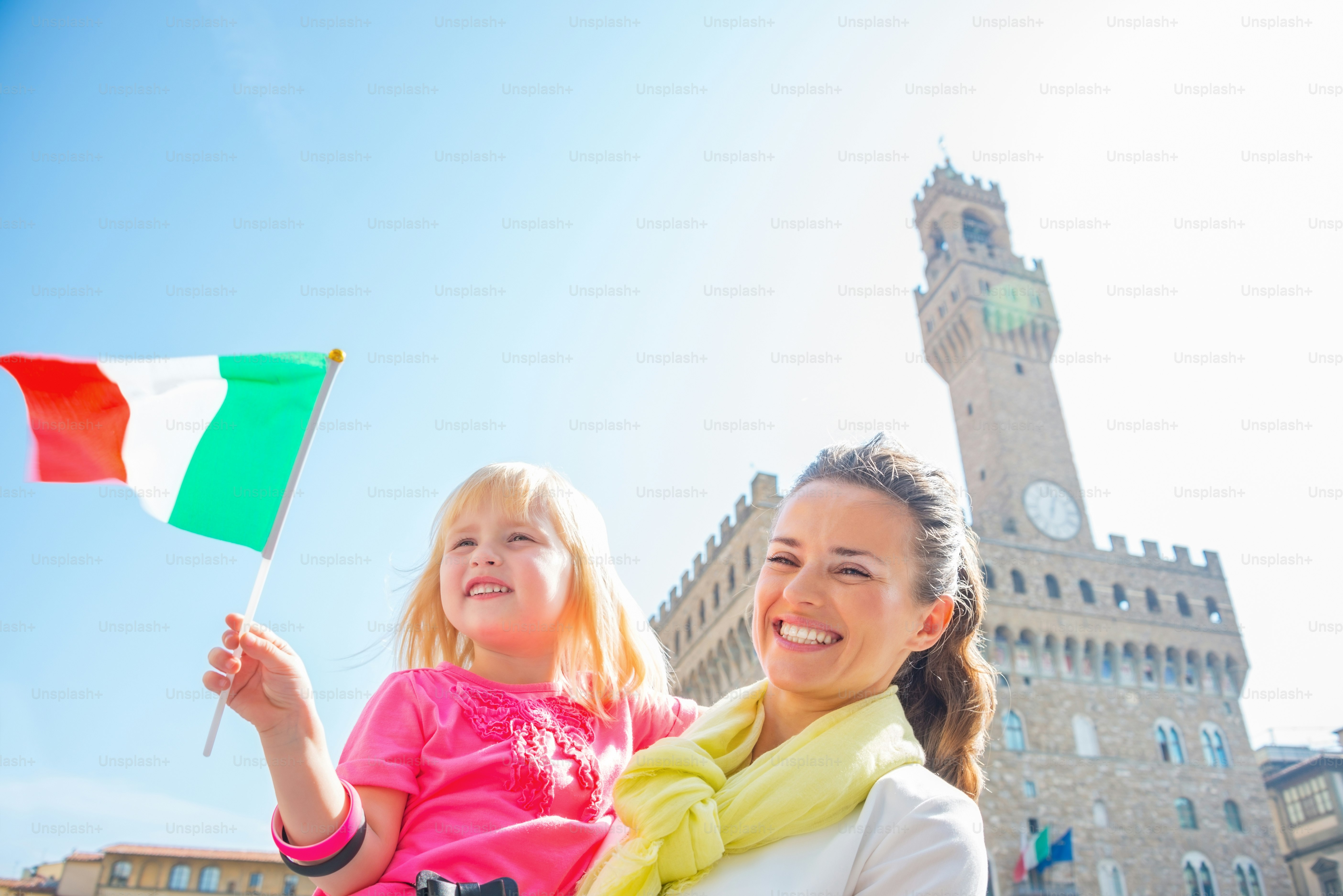 Happy mother and baby girl with flag in front of palazzo vecchio in florence, italy