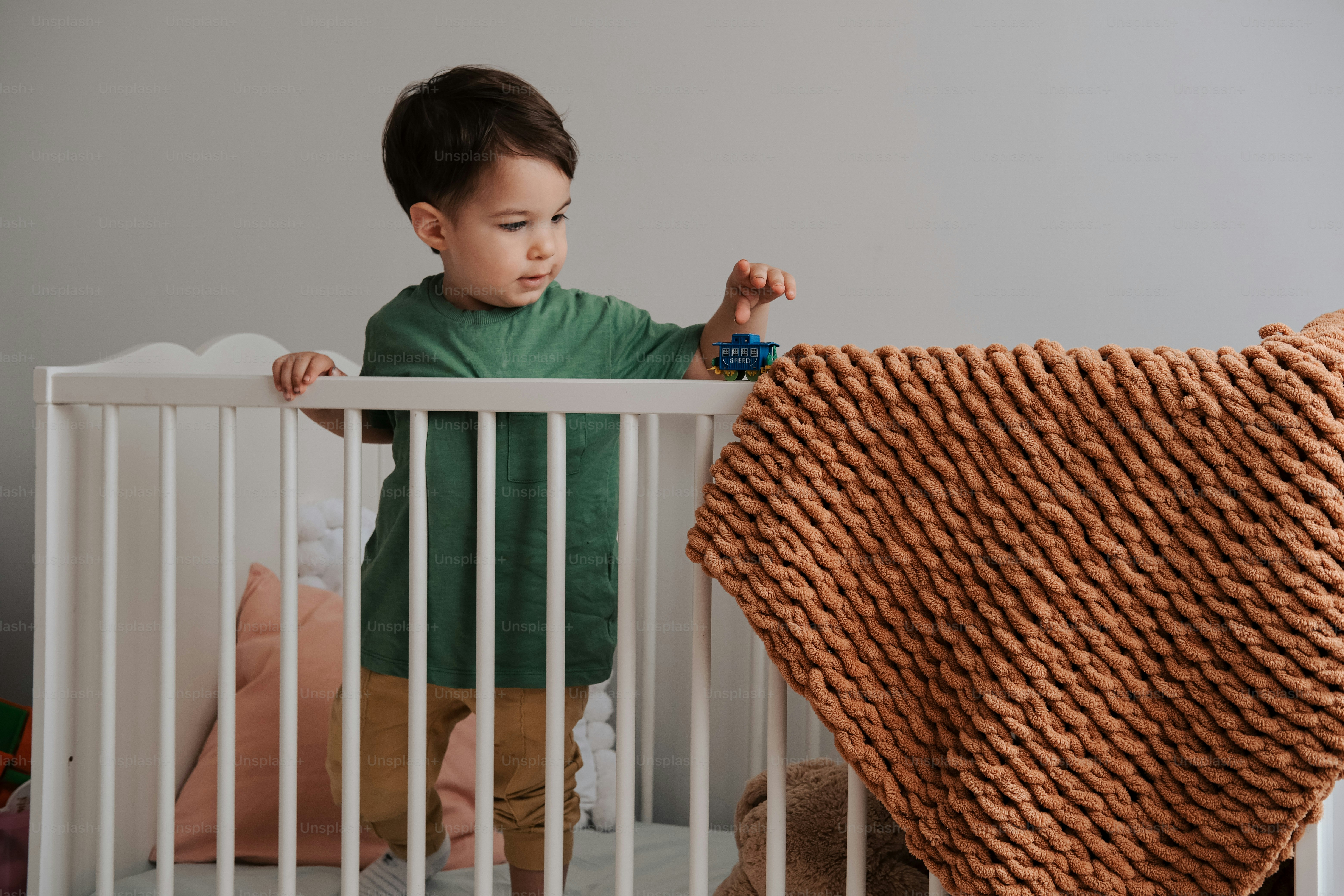 a little boy that is standing in a crib