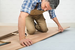 大工が自宅に新しいラミネートフローリングの床を設置する