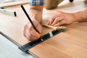 Close-up Of A Worker Drawing A Mark On Laminate Using Ruler