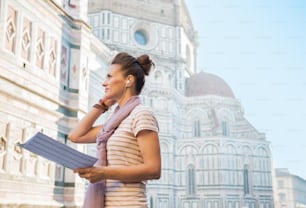 Mujer joven con mapa y audioguía frente a Cattedrale di Santa Maria del Fiore en Florencia, Italia