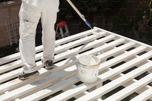 Maler rollt weiße Farbe auf die Oberseite einer Terrassenüberdachung.