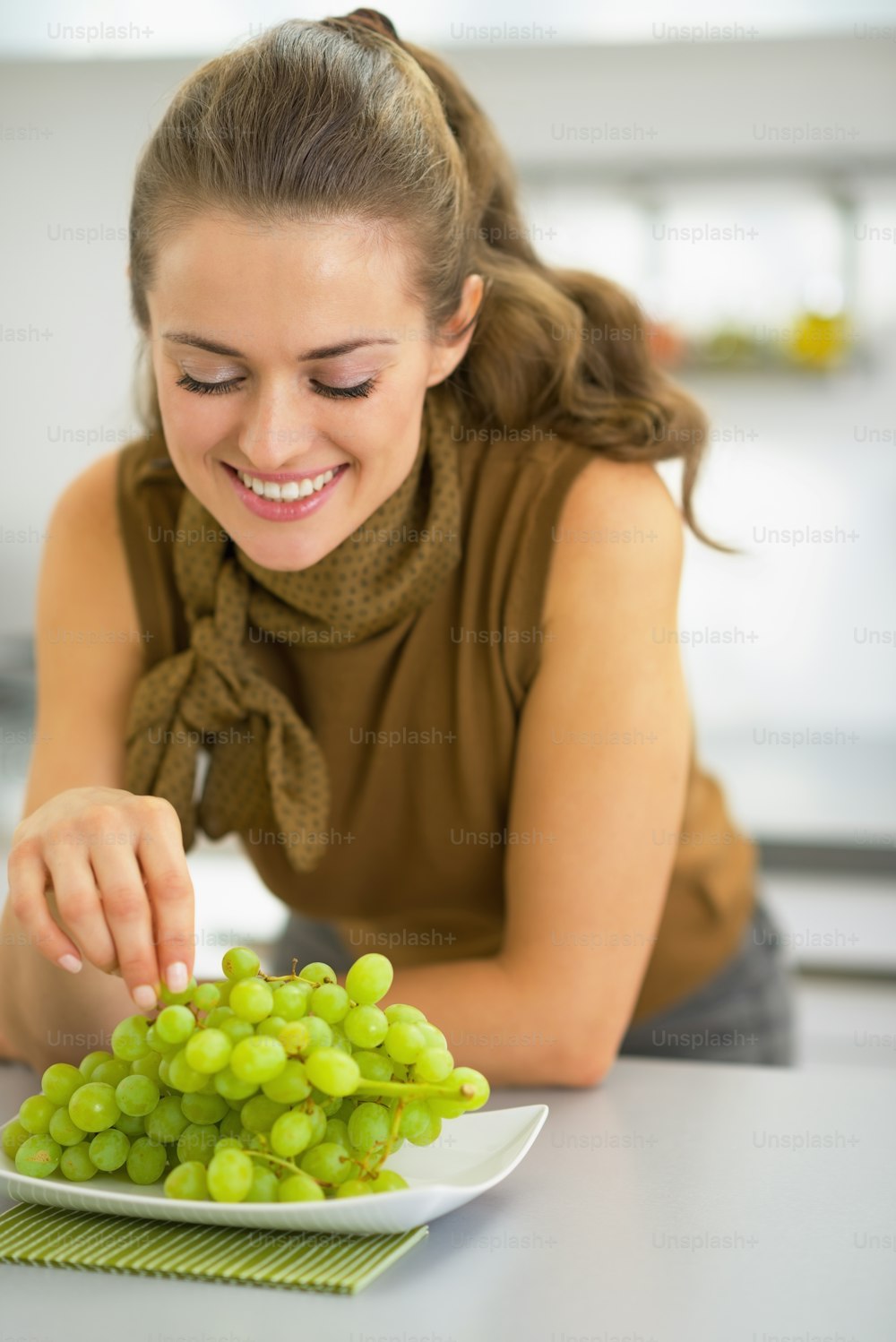 Happy young housewife eating grape