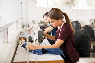 Vista de perfil de una línea de producción en una fábrica textil con personas que usan máquinas de coser