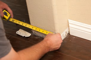 Contractor Measuring for New Baseboard with Bull Nose Corners and New Laminate Flooring Abstract.