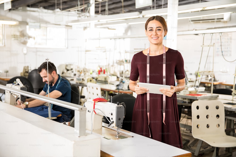 Retrato de una hermosa supervisora joven sosteniendo una tableta en una fábrica textil