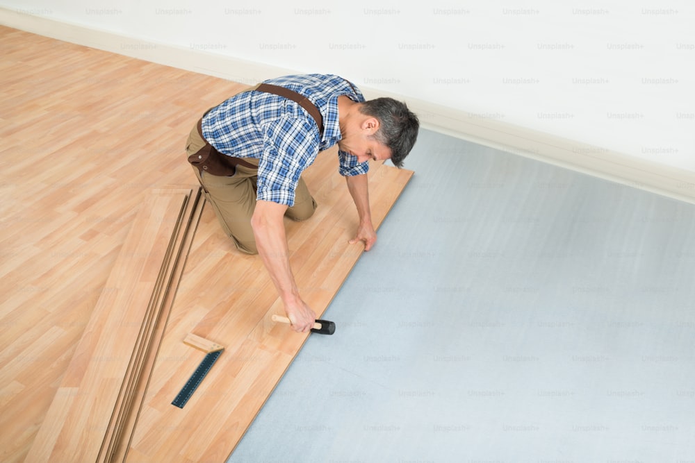 Carpinteiro instala novo piso de madeira laminada em casa