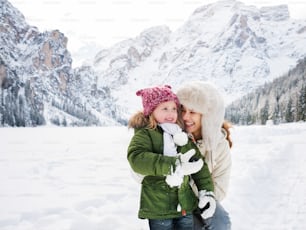 Winter outdoors can be fairytale-maker for children or even adults. Happy mother and child playing outdoors in front of snowy mountains