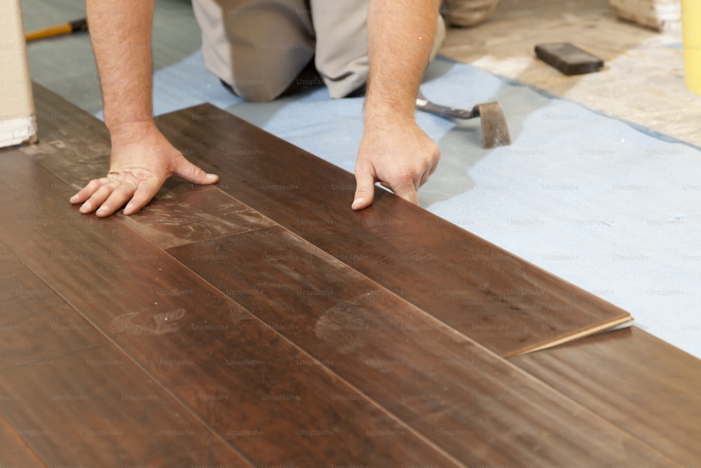 Uomo che installa nuovi pavimenti in legno laminato astratto.