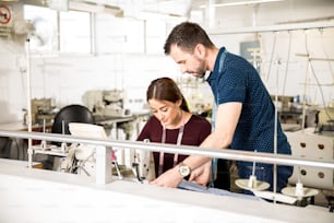 Male supervisor and a female tailor looking for ways to improve work in a textile factory