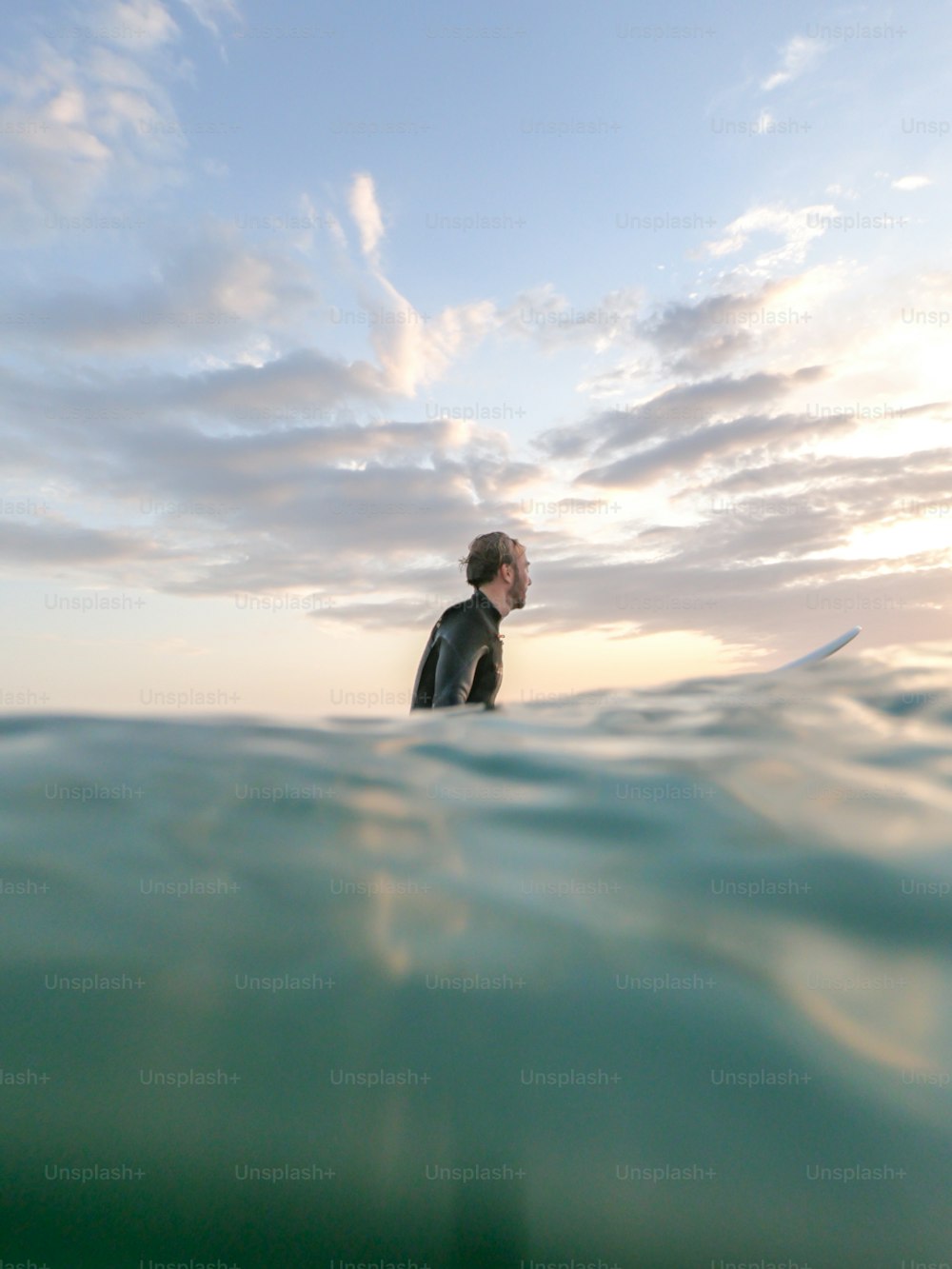 海のサーフボードの上に立つウェットスーツの男