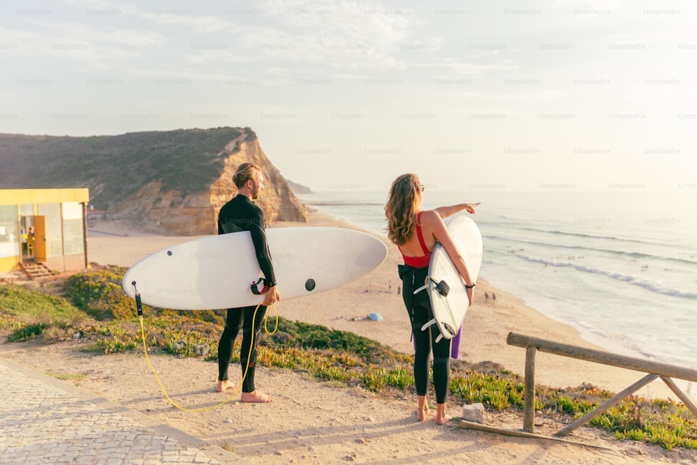 a man and a woman holding surfboards on a beach