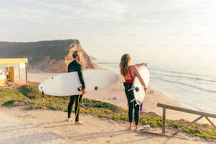 a man and a woman holding surfboards on a beach