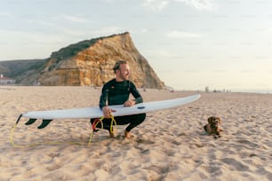 a man holding a surfboard on top of a sandy beach