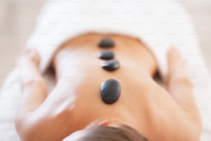 Nahaufnahme einer entspannten jungen Frau, die eine Hot-Stone-Massage erhält