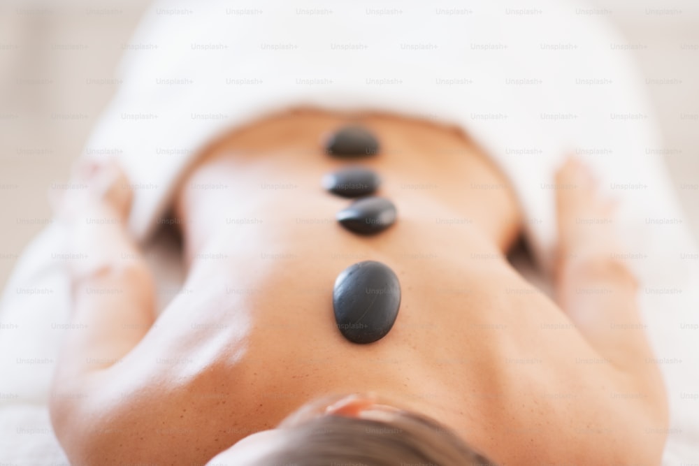Primer plano de una joven relajada que recibe un masaje con piedras calientes