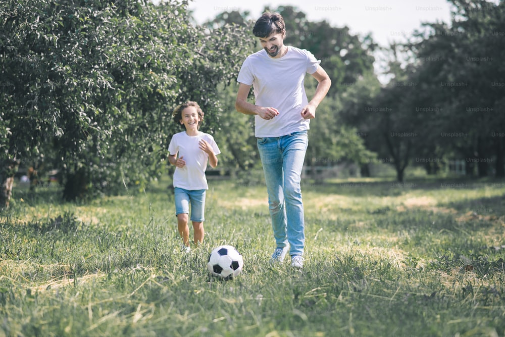 Fútbol. Niño de cabello oscuro y su padre jugando con la pelota