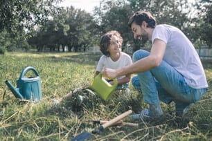 Jardinage. Un garçon aux cheveux noirs et son père arrosent les plantes dans le jardin