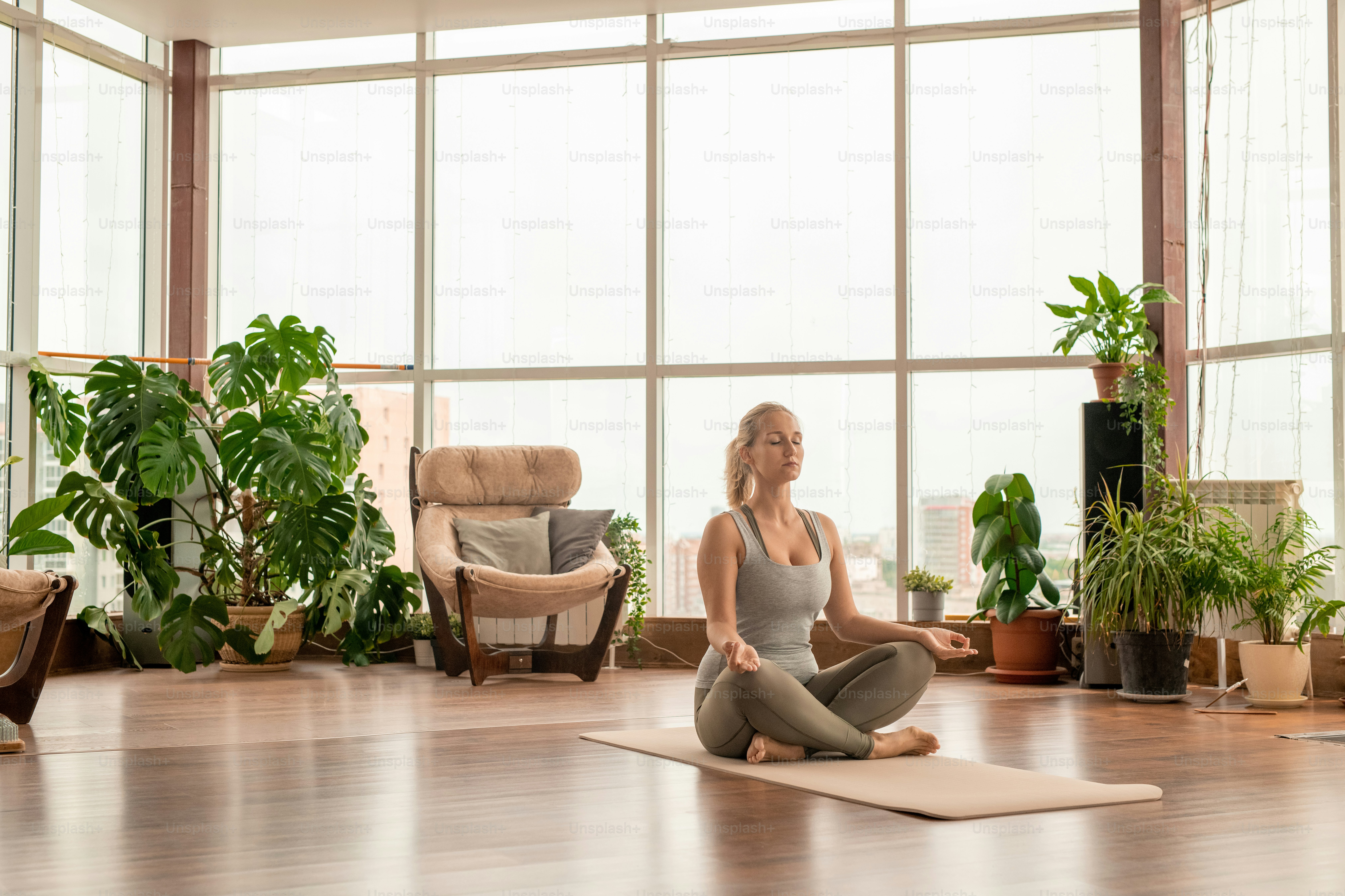 A serene yoga studio with sunlight streaming through the windows, plants, and meditation mats.