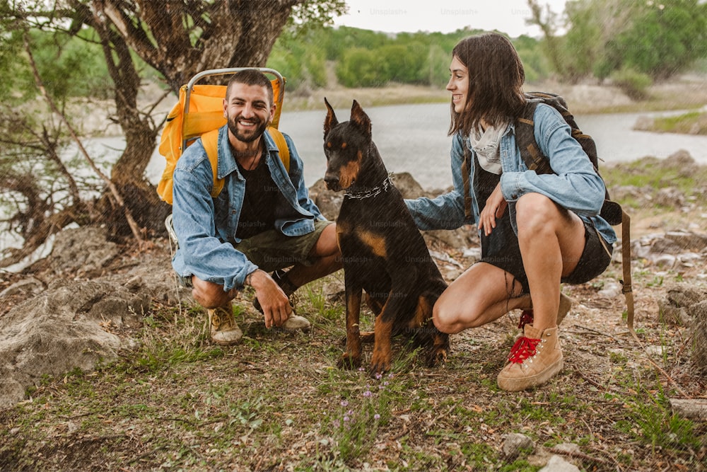 Coppia di escursionisti Trek e il loro cane che camminano sotto la pioggia trekking su trail trek con zaini sano stile di vita attivo.