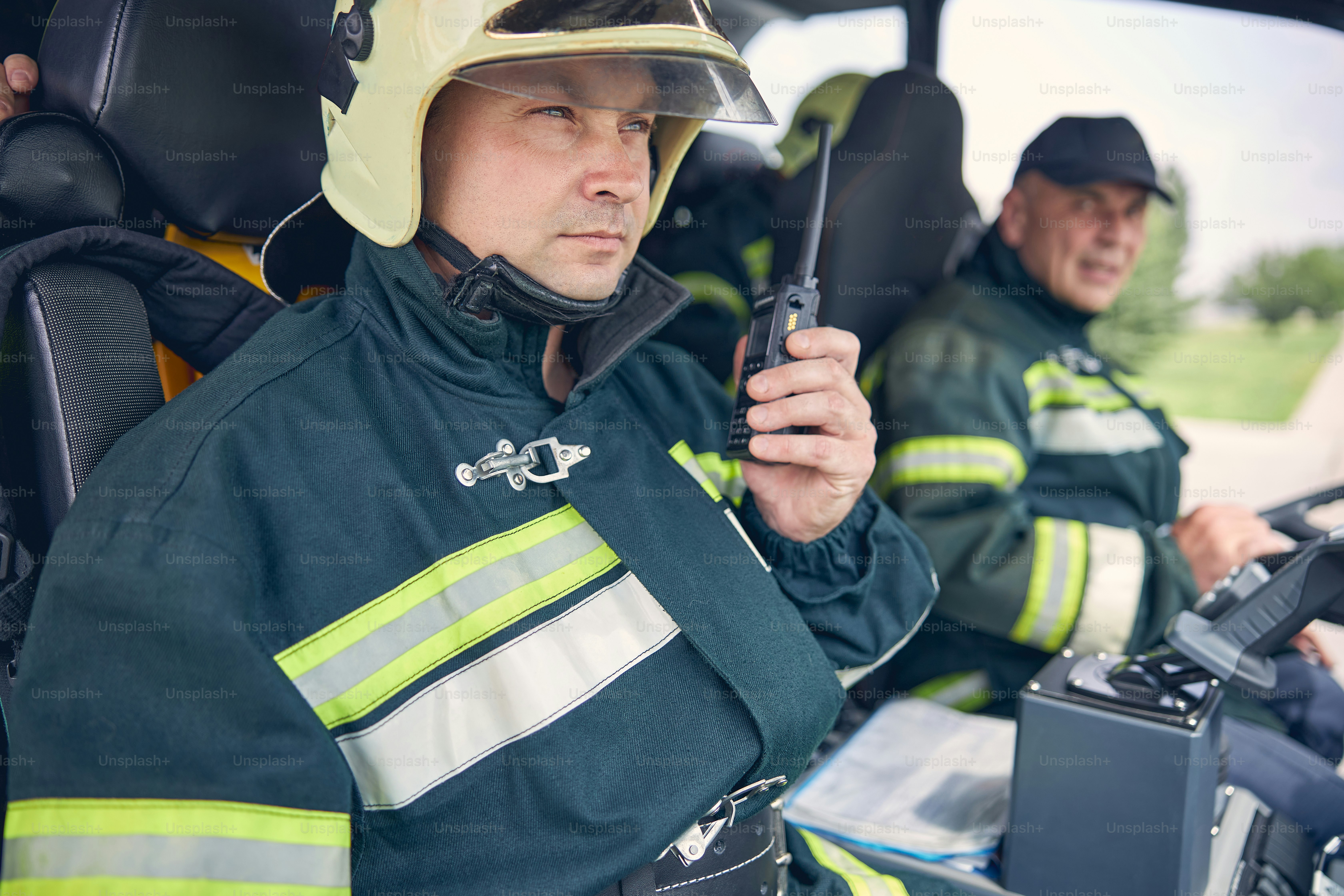 Back view portrait of two firefighters in yellow helmets using ...