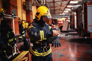 Pompiere che indossa l'uniforme protettiva e si prepara per l'azione mentre si trova nella stazione dei pompieri.