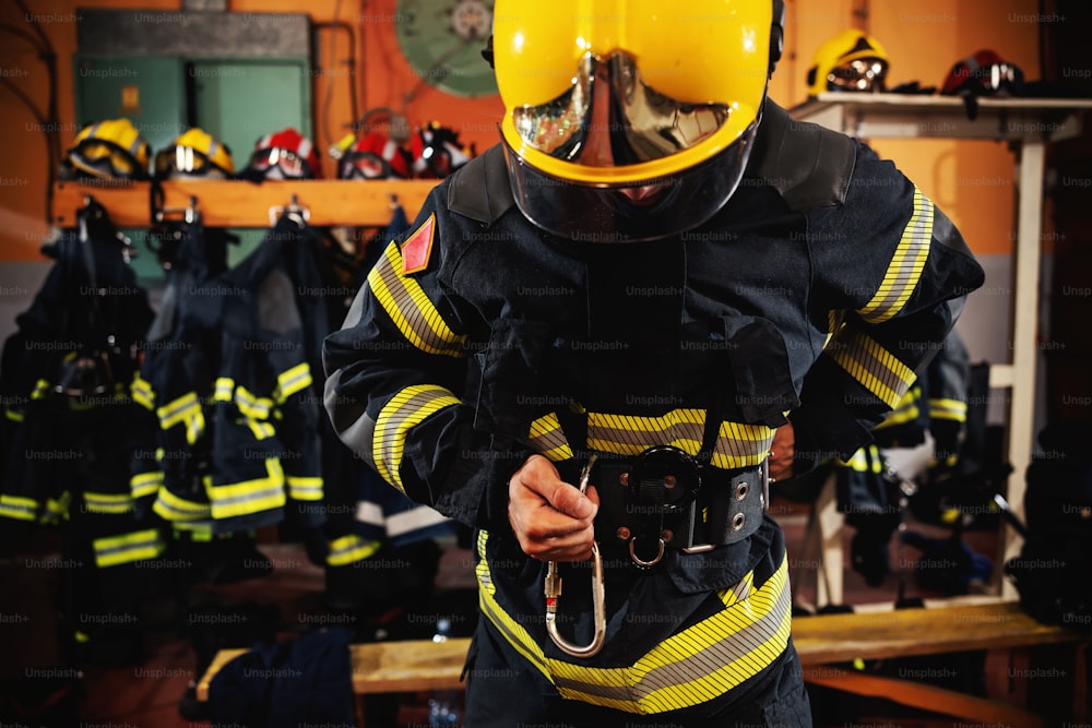 Feuerwehrmann zieht Schutzuniform an und bereitet sich auf den Einsatz vor, während er in der Feuerwache steht.