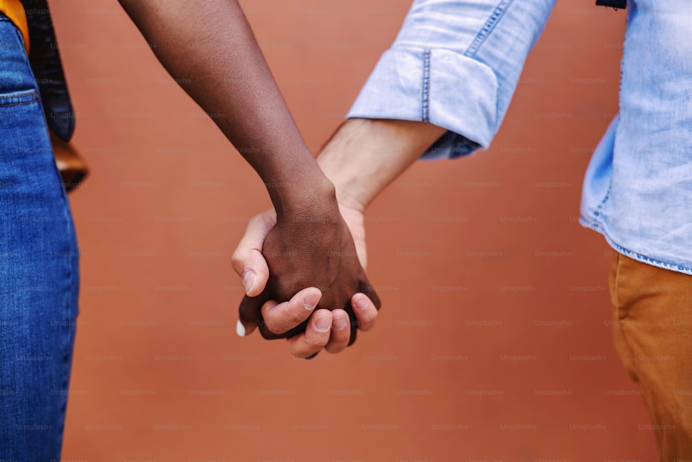 Closeup de casal multicultural de mãos dadas.