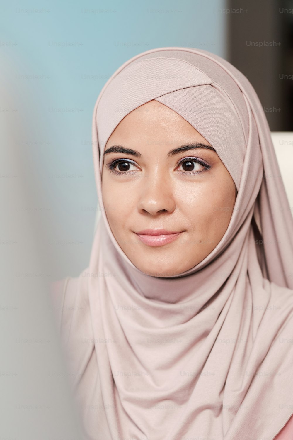 Hermosa mujer musulmana joven con hijab rosa mirando el monitor en una oficina moderna
