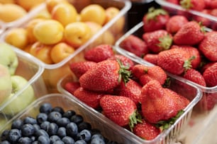 Close-up of fresh fruits and berries in plastic containers placed on counter at food market