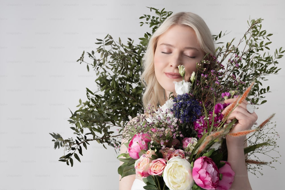 Attractive blonde lady closing eyes and smiling while holding beautiful bouquet