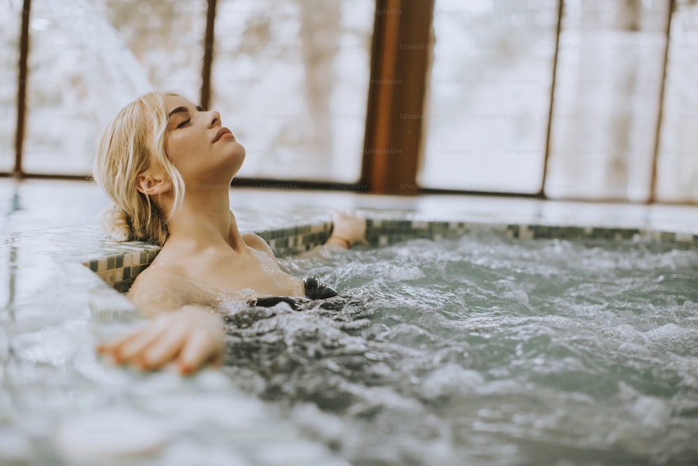 Hübsche junge Frau, die sich in der Whirlpool-Badewanne entspannt