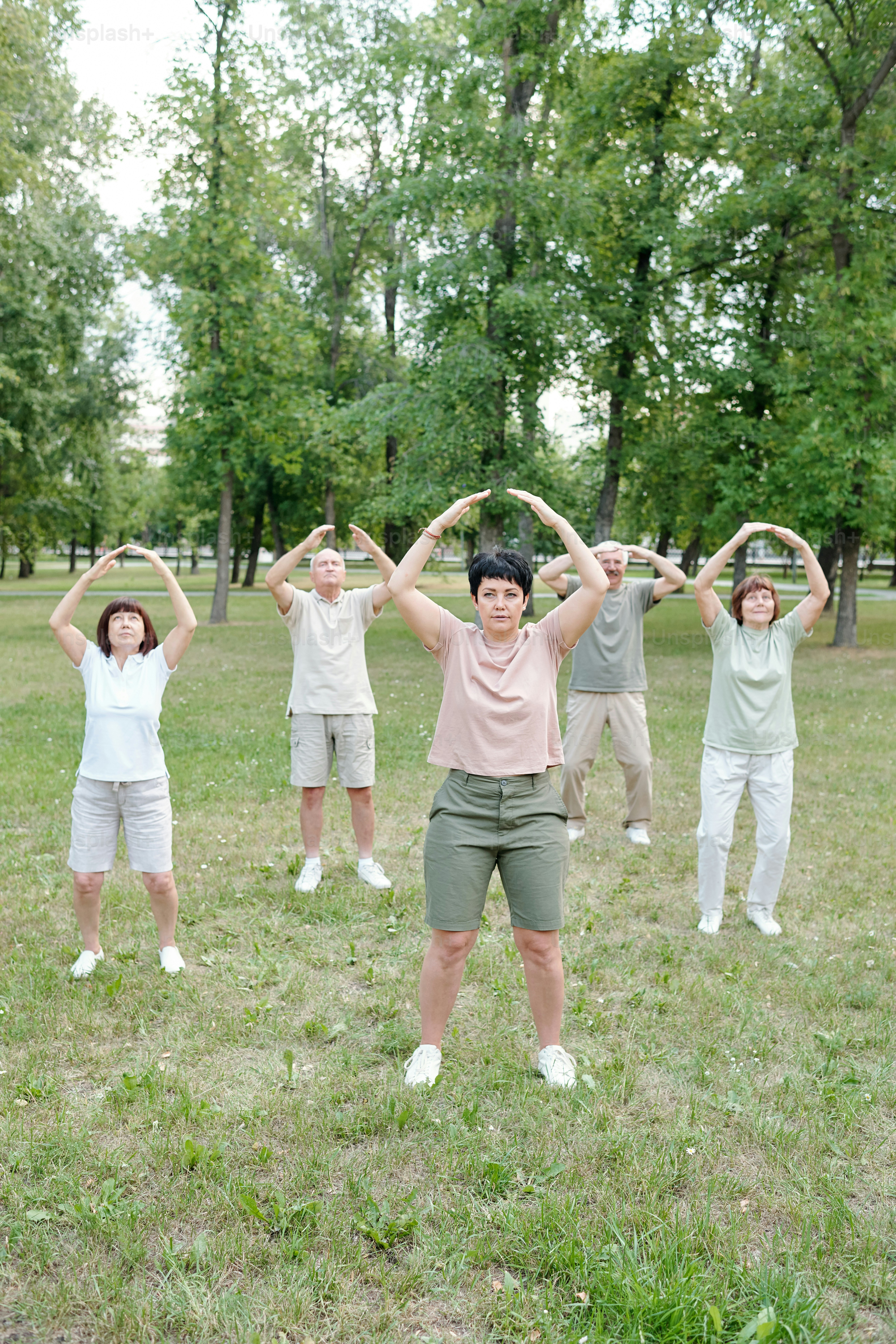 Allenatore maturo qualificato che mostra l'esercizio di qigong agli studenti senior nel parco della città