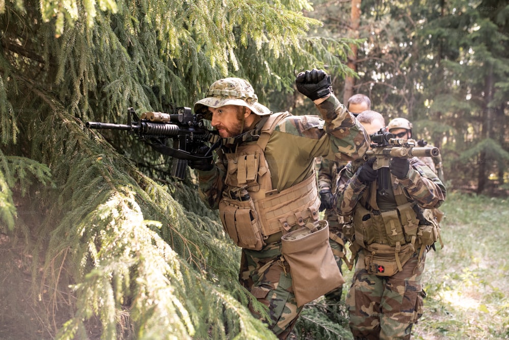 Líder militar mirando a través de la mira telescópica del rifle y preparando a su equipo para el ataque