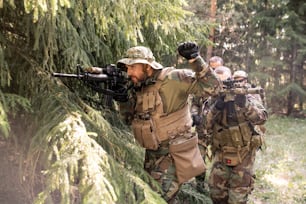 Líder militar mirando a través de la mira telescópica del rifle y preparando a su equipo para el ataque