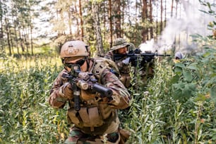 Eine Gruppe von Soldaten in Uniform, die sich während einer militärischen Aufklärungsoperation durch Waldbüsche bewegen