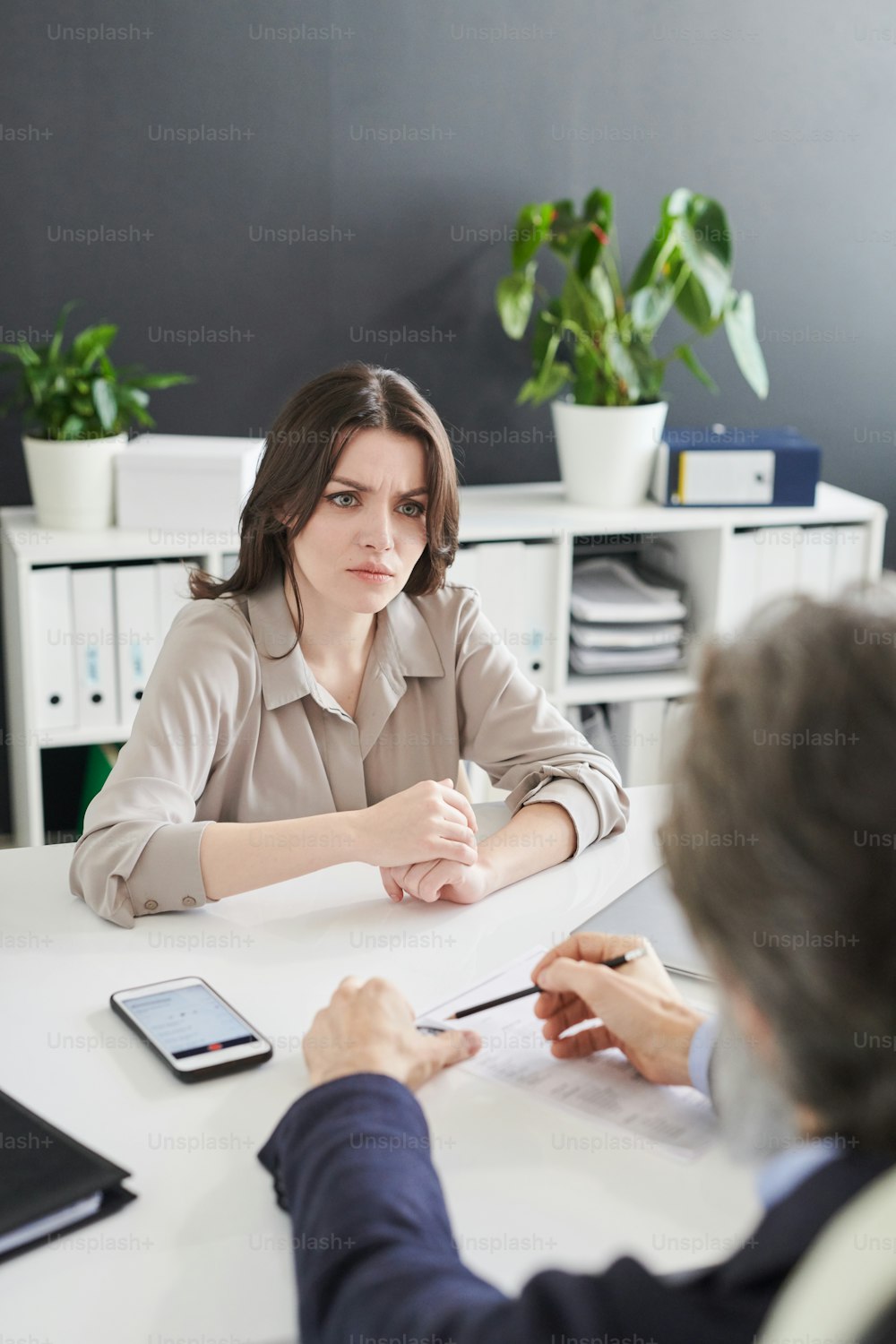 Young woman feeling confused with absurd questions HR manager asking her at job interview, vertical high angle shot