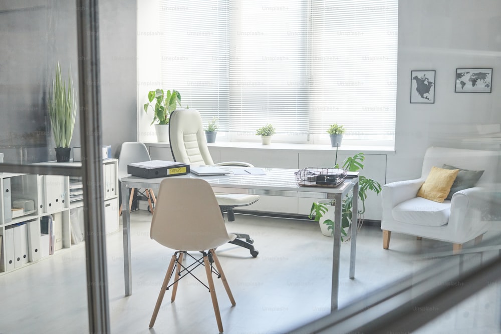 Nessuna persona attraverso il vetro Scatto dell'interno minimalista del posto di lavoro nella moderna stanza dell'ufficio in colore bianco